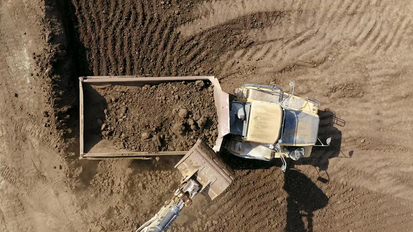 Compact excavator working a site, seen from above